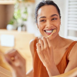 Woman smiling while brushing her teeth