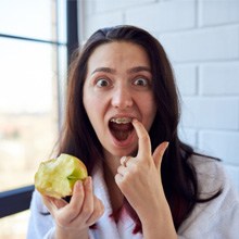 a girl with braces eating an apple