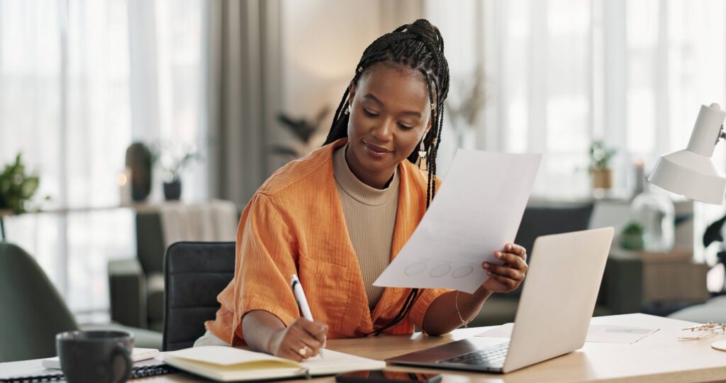 Smiling woman taking notes while working in office