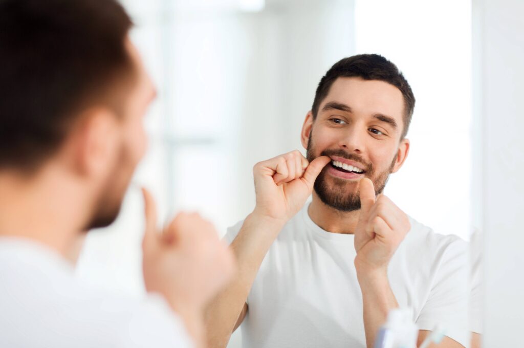 Closeup of smiling man flossing in bathroom