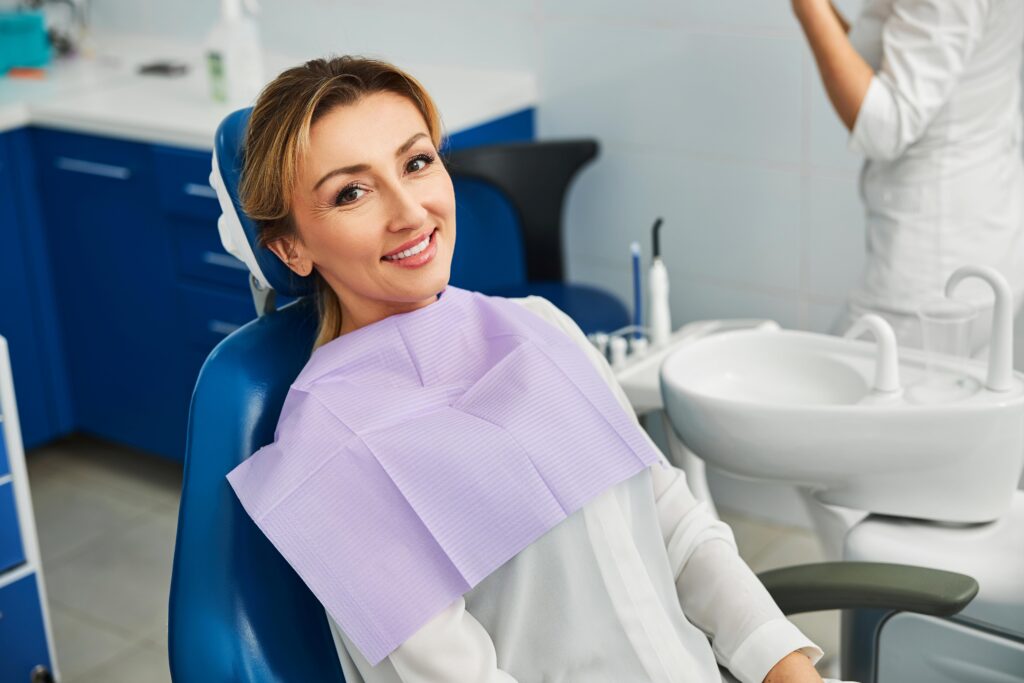 Woman with purple bib smiling in treatment chair